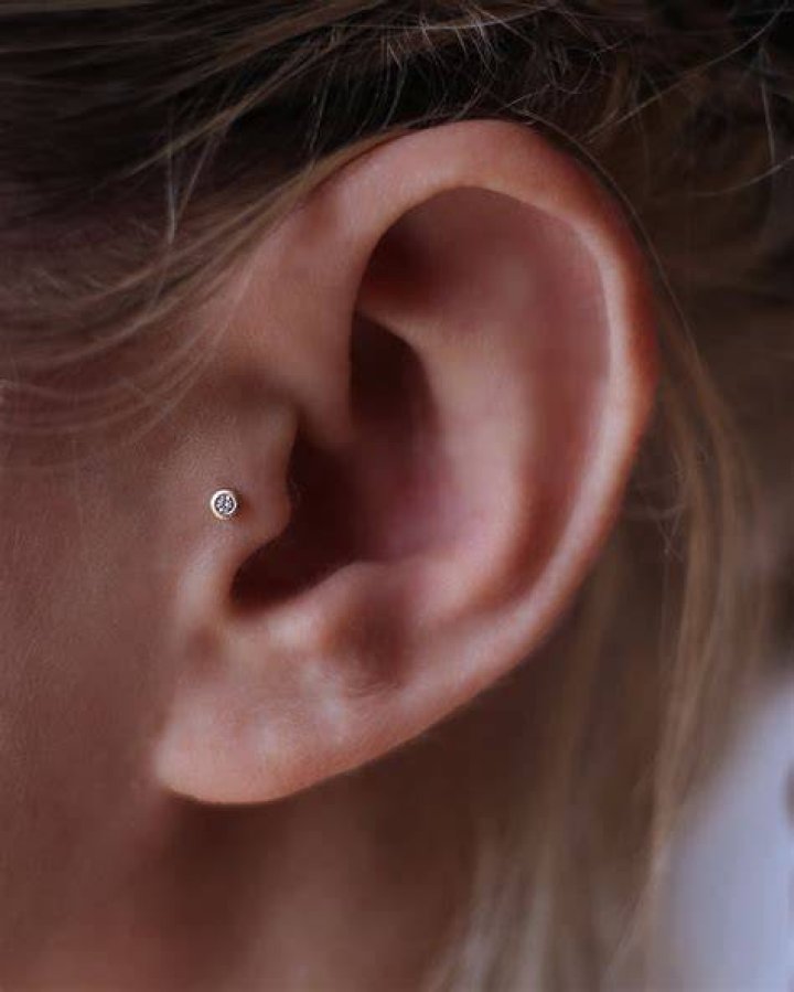Tragus piercing with a stud earring (L) and in a love shaped earing (R)